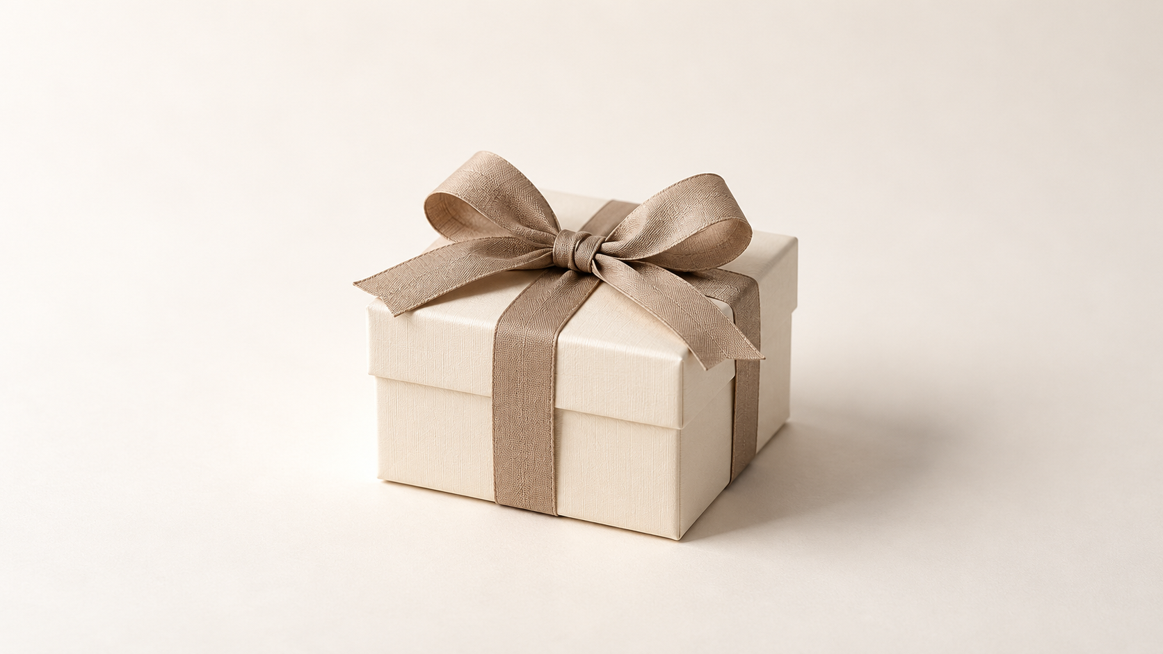 Cremefarbene Geschenkbox mit Schleife – Symbolbild, keine Produktabbildung